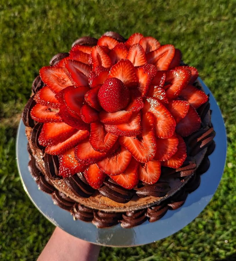 Round cake topped with strawberries and chocolate drizzle