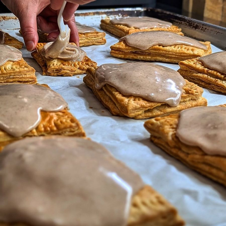 Baker piping icing onto apple turnovers