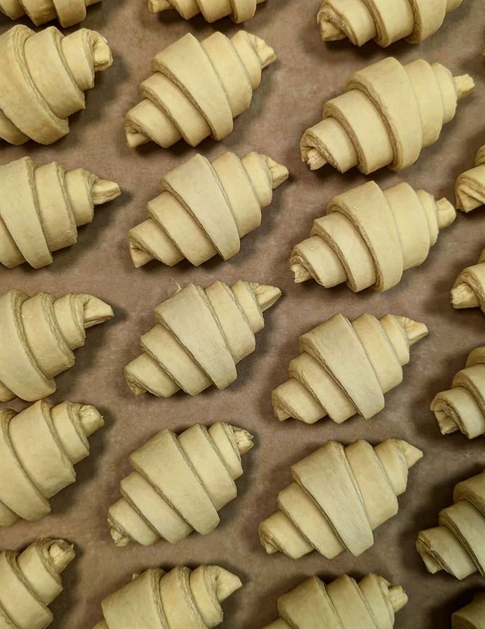 Unbaked croissants arranged on a parchment-lined baking sheet