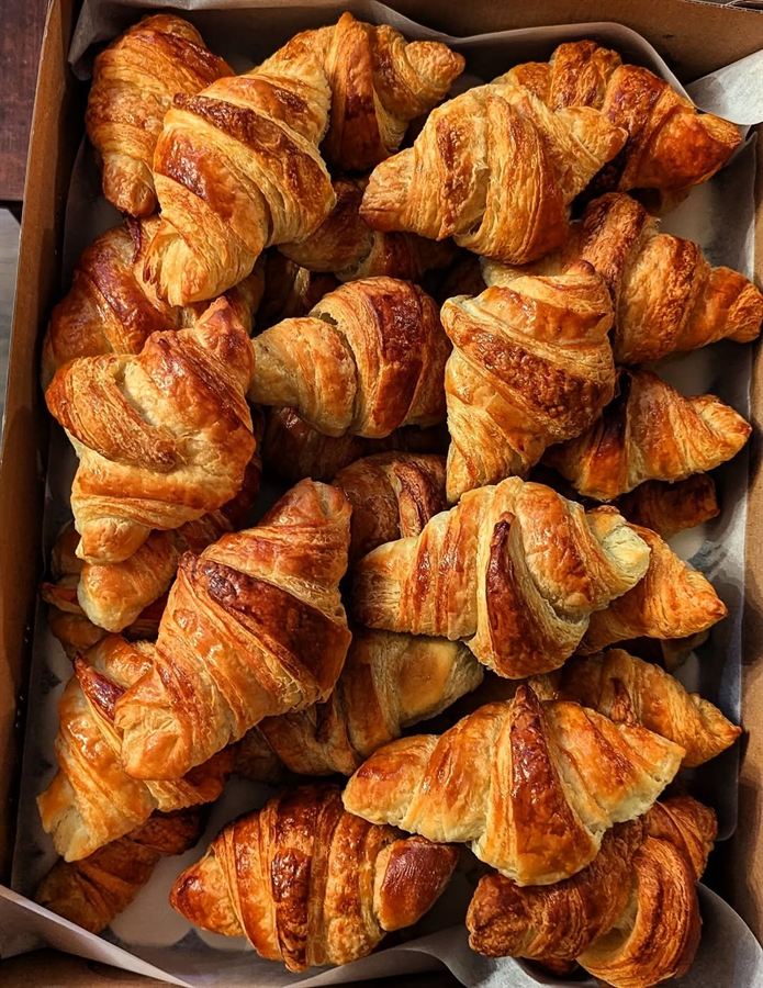 Tray of freshly baked croissants in a parchment-lined box