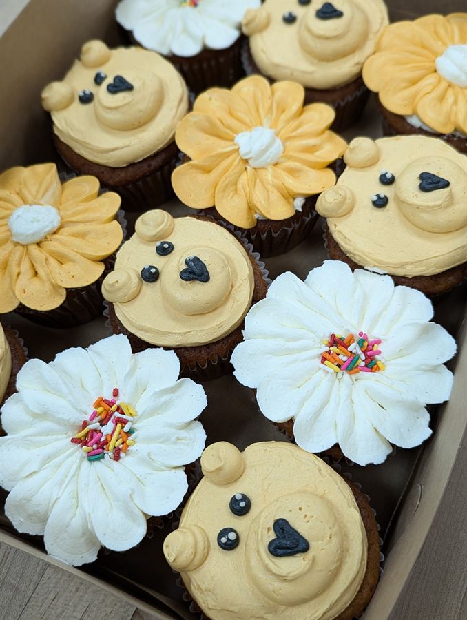 Box of cupcakes frosted as teddy bear faces and white and yellow daisies